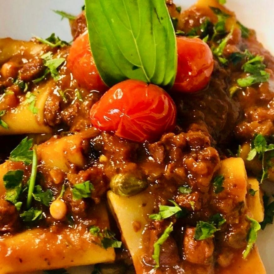 Paccheri al ragu di polpo con pomodorini confit, capperi e prezzemolo, ripresi da vicino