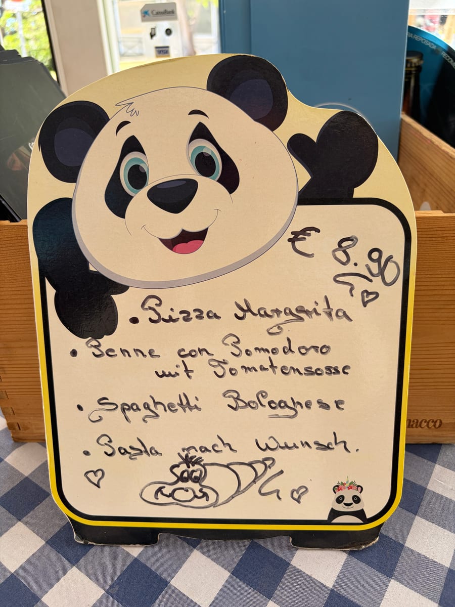 Il menu bambini scritto a mano su una lavagnetta a forma di panda: pizza margherita, penne al pomodoro, spaghetti bolognese, bibita e gelato, 8,90 eur