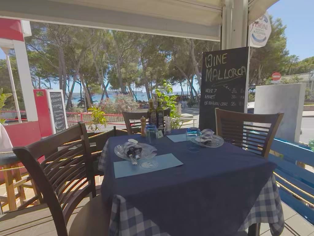 Tavolo apparecchiato con vista sul mare fra i pini e la lavagna WINE MALLORCA con i vini dell isola e i loro prezzi